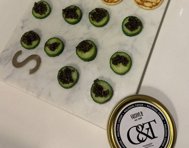 Blini and cucumber canapes topped with Kaluga Hybrid caviar