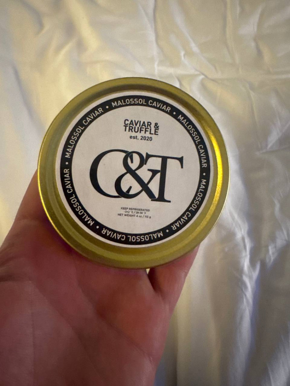 Sealed tin of caviar with the label showing keep refrigerated and the net weight